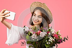 A radiant young woman in a chic summer outfit and straw hat takes a selfie