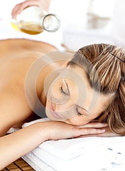 Radiant young woman having a back massage with oil