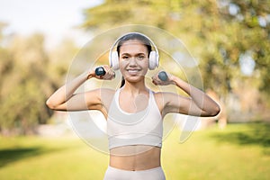 Radiant young woman wearing white workout clothes and headphones enjoys a sunny day