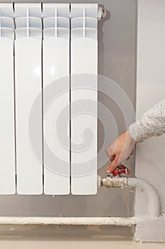 Radiator adjustment closeup. Woman`s hand adjusting regulating valve for supplying heat