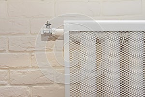 Radiator heating device against a white brick wall. cozy house with modern interior room close up