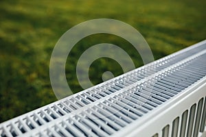 Radiator mesh, green lawn background, ecological heating concept