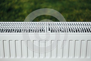 Radiator mesh, green lawn background, ecological heating concept