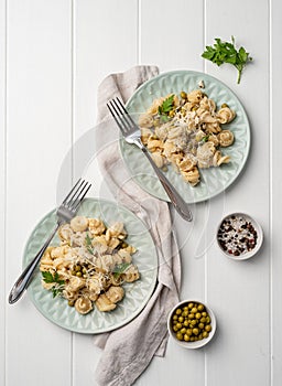 radiatori pasta with cherry tomatoes, cheese and parsley in white plate on wooden background