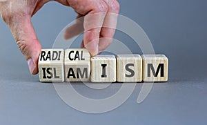 Radicalism or islamism symbol. Businessman turns cubes and changes the word `radicalism` to `islamism`. Beautiful grey backgro