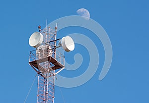 Radio cellular antenna over blue sky and big half moon