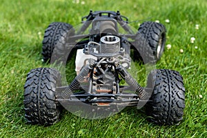 Radio-controlled car with internal combustion engine for nitro fuel, with one cylinder, standing on green grass.