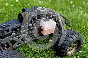 Radio-controlled car with internal combustion engine for nitro fuel, with one cylinder, standing on green grass.