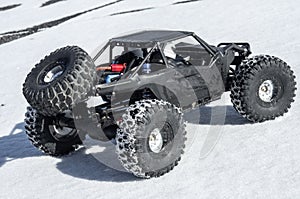 Radio controlled car models: a small black buggy toy with dirty splashes stands in the snow.