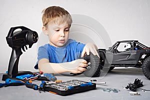 Radio controlled models: A little boy in a blue T-shirt is repairing his RC car buggy.