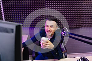 radio host drinking tea conducts a live broadcast in professional radio studio.