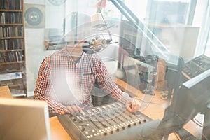 Radio host operating sound mixer in studio