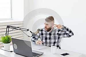 Radio host, streamer and blogger concept - Handsome man working as radio host at radio station sitting in front of