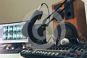 Radio microphone, mixing console and headphones on the background of the monitor