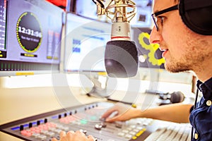 Radio moderator is sitting in a modern broadcasting studio and talking into the microphone