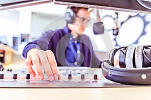 Radio moderator is sitting in a modern broadcasting studio and talking into the microphone