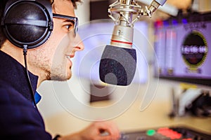 Radio moderator is sitting in a modern broadcasting studio and talking into the microphone