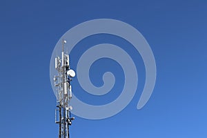 Radio tower with antennas on a blue sky background. Metal construction. Wireless tezhnologii. Transmission of a tele-radio signal.