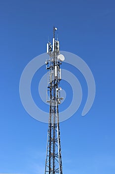 Radio tower with antennas on a blue sky background. Metal construction. Wireless tezhnologii. Transmission of a tele-radio signal.