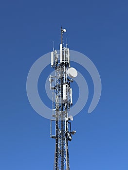 Radio tower with antennas on a blue sky background. Metal construction. Wireless tezhnologii. Transmission of a tele-radio signal.