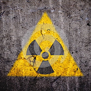 Radioactive atomic ionizing radiation danger warning symbol in triangular yellow shape painted massive cracked concrete wall