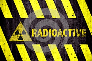 Radioactive ionizing radiation danger symbol and word with yellow and black stripes painted on a massive concrete wall