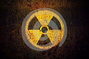 Radioactive: round yellow radioactive ionizing radiation danger symbol painted on a massive rusty metal wall.