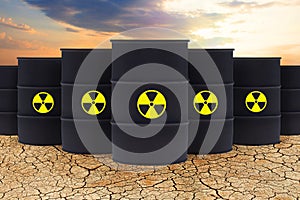 Radioactive waste against sky clouds and dried depleted land. Radioactive waste barrels. Environment protection photo