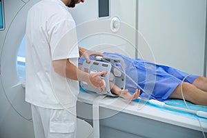 Radiographer preparing client for magnetic resonance imaging of lower arm