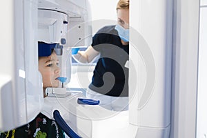 Radiographer taking panoramic teeth radiography to a little boy using modern x-ray machine.