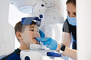 Radiographer taking panoramic teeth radiography to a little boy using modern x-ray machine. photo