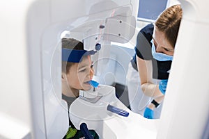 Radiographer taking panoramic teeth radiography to a little boy using modern x-ray machine. photo