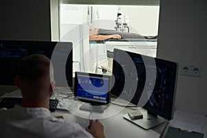 Radiologic technologist is performing computed tomography on adult man