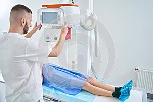 Radiologic technologist is preparing adult man for digital abdominal radiography photo
