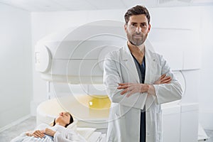 Radiologist on background of MRI or CT or PET Scan with female patient undergoing procedure
