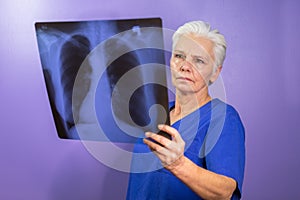 Radiologist in a blue uniform studying an x-ray