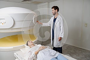 Radiologist controls MRI or CT or PET Scan with female patient undergoing procedure