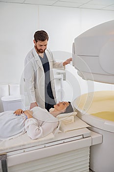 Radiologist controls MRI or CT or PET Scan with female patient undergoing procedure