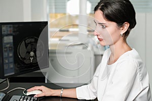 Radiologist woman reading a CT scan. Female doctor running CT scan from control room at hospital.