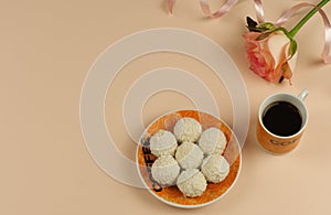 Raffaello sweets on a saucer, a cup of black coffee, a pink rose.