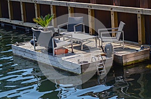 Raft with a motor with outdoor furniture, chairs, deck chairs and a stom in clear weather on the shore of Copenhagen Denmark