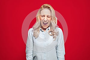 Rage woman looking at camera and screaming, isolated on red background. Frustrated girl