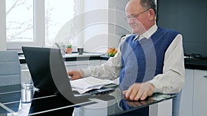 Rageful pensioner businessman throws documents sitting in front of computer