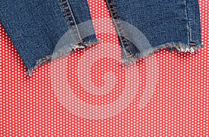 Ragged jeans on red creative backgroundin polka dot. Top view.