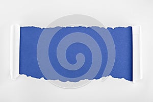 Ragged textured white paper with curl edges on blue background.