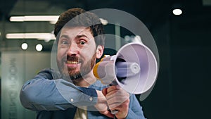 Raging flushed male screaming with megaphone and waving hand in office