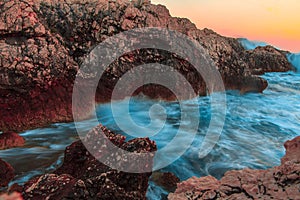 Raging ocean waves breaking on rocks at sunset