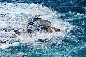 Raging sea flows over lave rocks on shore line