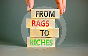 Rags or riches symbol. Concept words From rags to riches on wooden blocks. Beautiful grey table grey background. Businessman hand