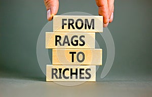 Rags or riches symbol. Concept words From rags to riches on wooden blocks. Beautiful grey table grey background. Businessman hand